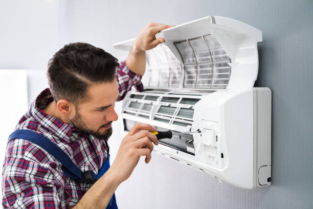 Happy Male Technician Repairing Air Conditioner With Screwdriver